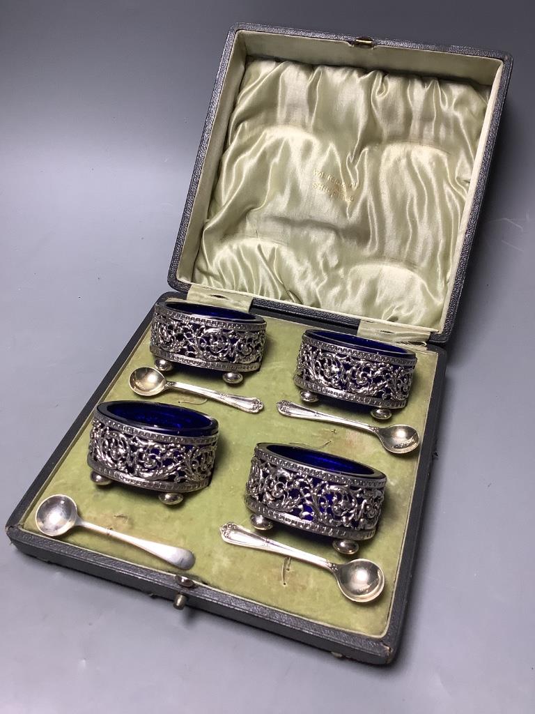 A cased set of four Edwardian, pierced silver oval salts, with blue glass liners, Sheffield, 1904 and four associated spoons